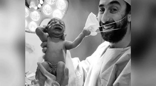 Fotografia anului – Un nou-născut îi smulge masca de protecție medicului: “Un semnal că ne vom da jos în curând măștile”
